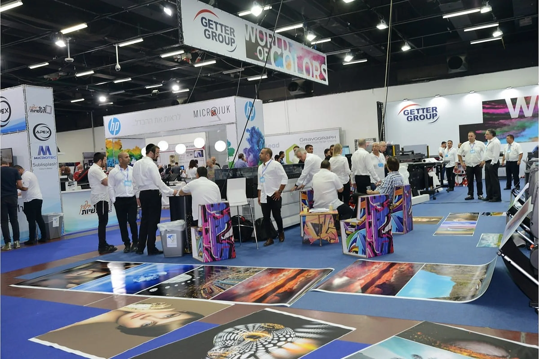 מבקרים בין הביתנים של Getter Group, HP ומיקרוג'וק בתערוכת ISPRINT באקספו תל אביב, הדפסות צבעוניות פרושות על הרצפה